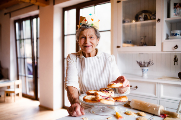 An elderly woman making cakes in a kitchen at home. Copy space.