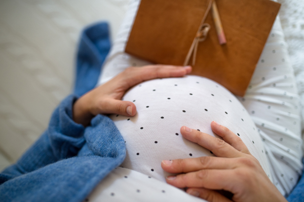 Top view of unrecognizable pregnant woman indoors at home, resting.