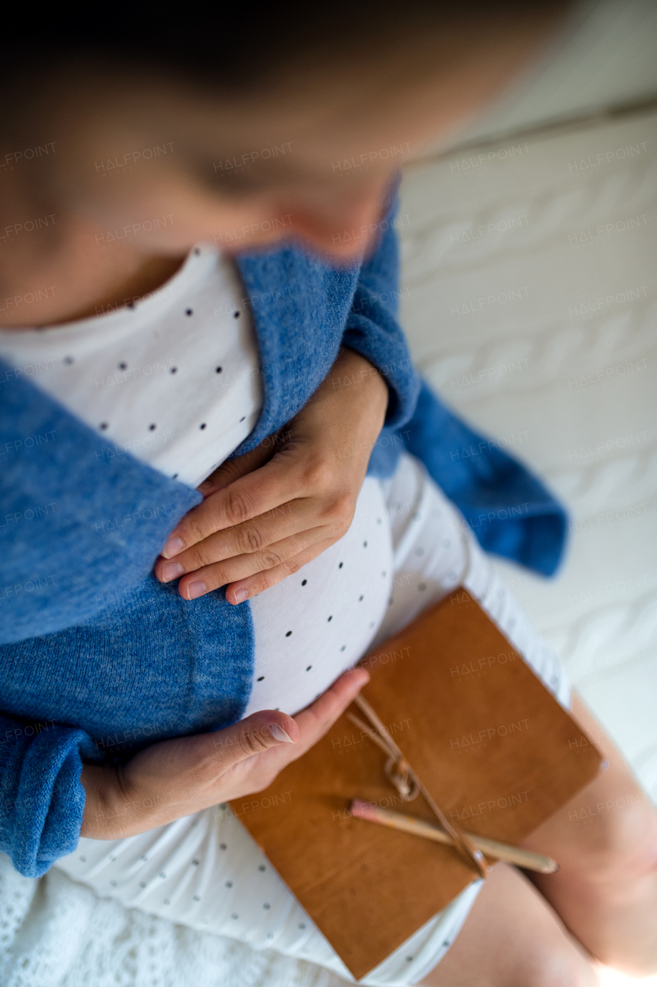 Top view of unrecognizable pregnant woman indoors at home, awaiting birth of baby.