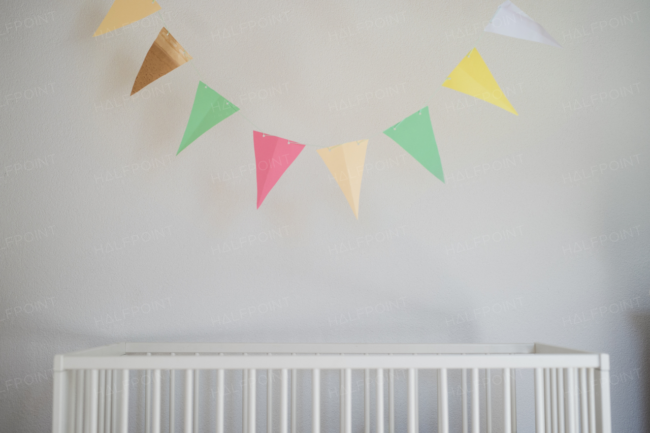 Cot in bedroom decorated for newborn baby. Copy space.