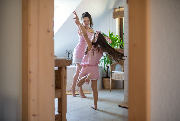 Portrait of happy pregnant woman with small daughter indoors in bathroom at home, having fun.