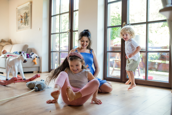 Happy pregnant woman with small children indoors at home, playing.