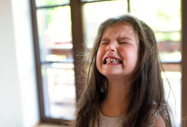 Portrait of angry and difficult small girl indoors, crying.