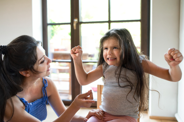 Portrait of mother and angry small girl indoors at home, tantrum concept.