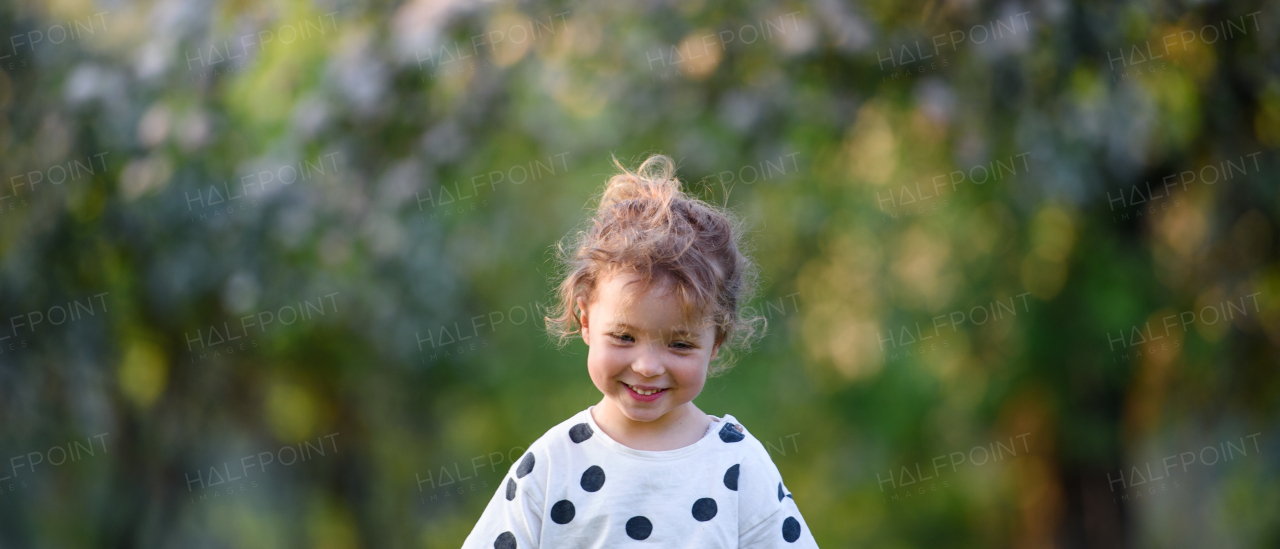 Front view of happy small girl walking outdoors in spring nature.