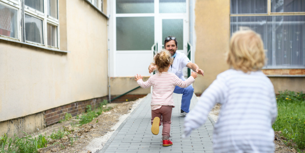 Happy children running to greet father doctor in front of hospital, end of coronavirus concept.