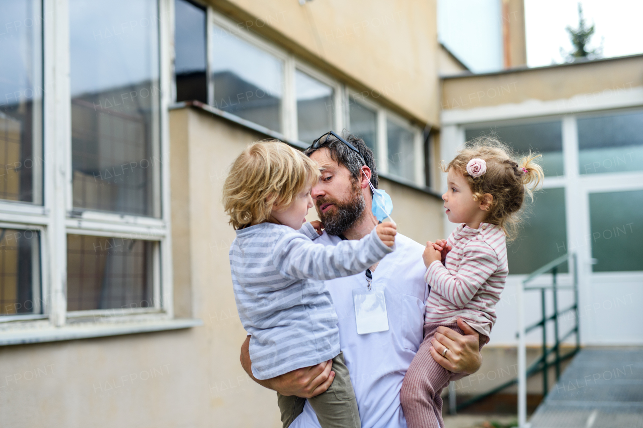 Happy children greeting father doctor in front of hospital, end of coronavirus concept.