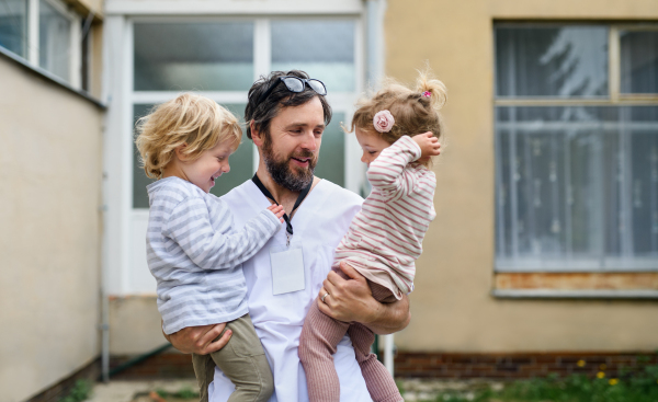 Happy children greeting father doctor in front of hospital, end of coronavirus concept.