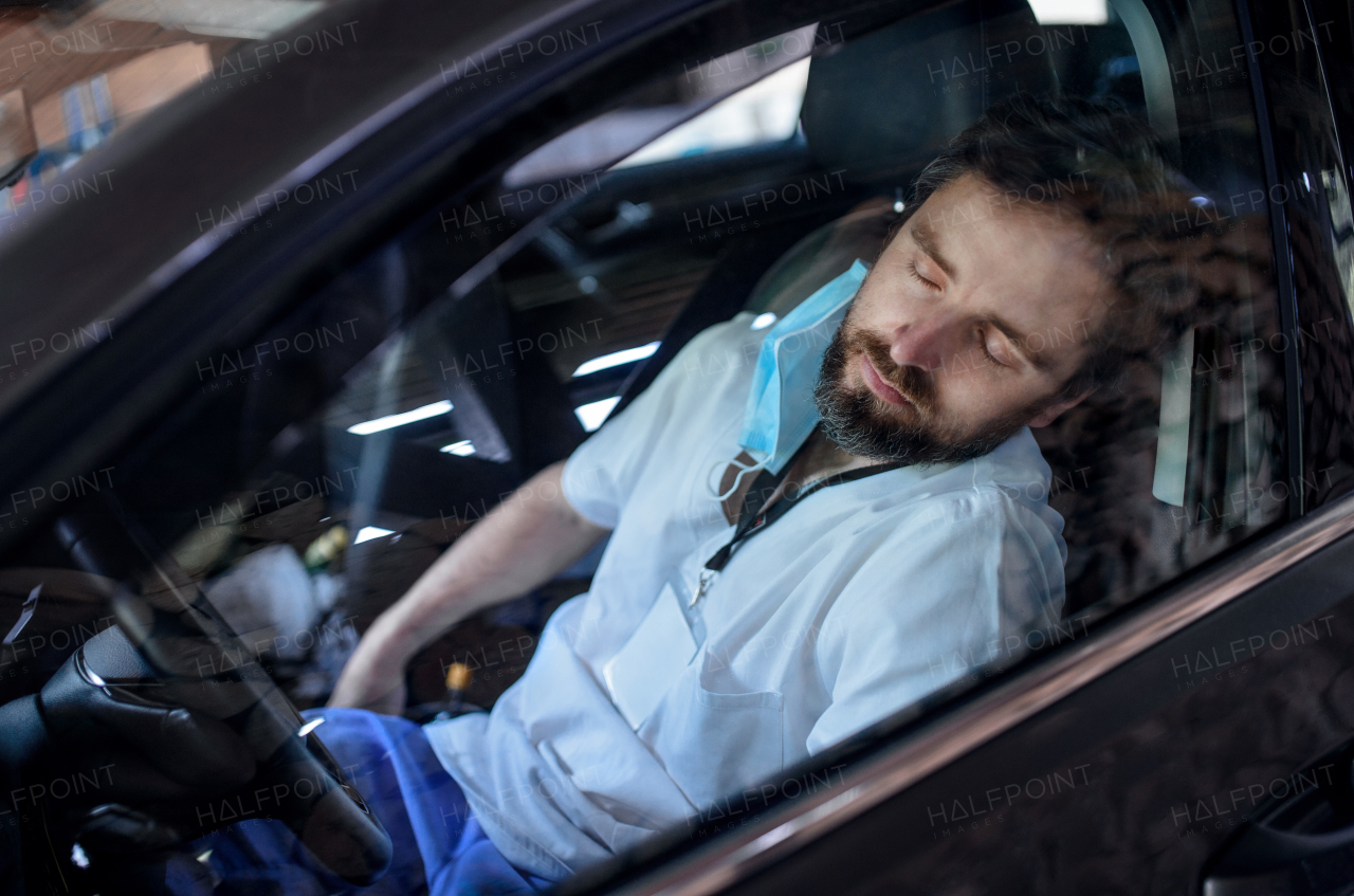 Top view of tired and exhausted doctor sitting in car after long and difficult shift, sleeping.