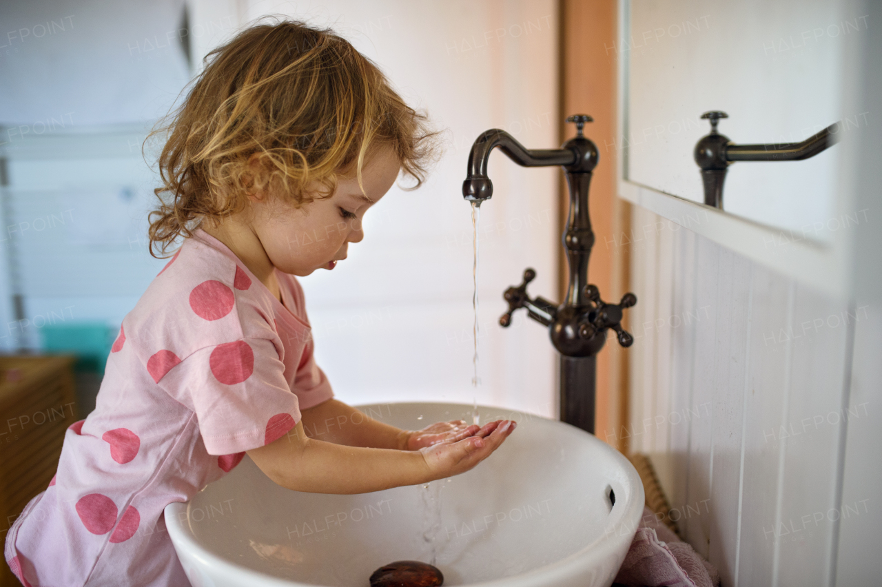 Side view of concentrated small toddler girl washing hands, corona virus and quarantine concept.