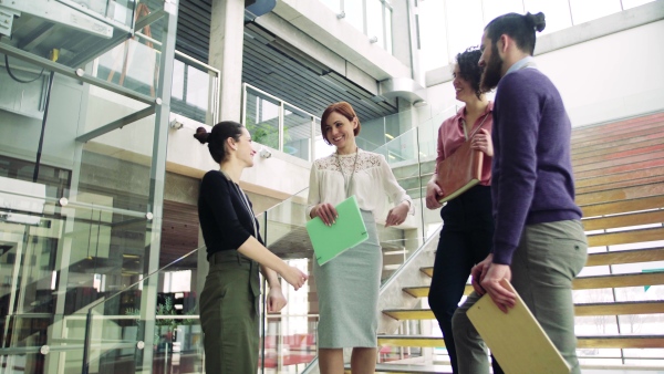 A group of young businesspeople standing on a staircase, talking.