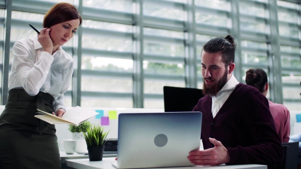 A group of young businesspeople working together in office, talking.