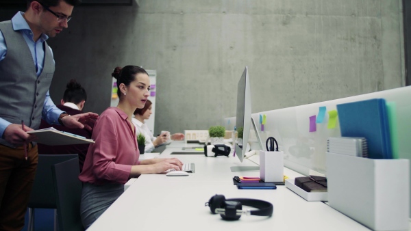 A group of young businesspeople working together in office, talking.