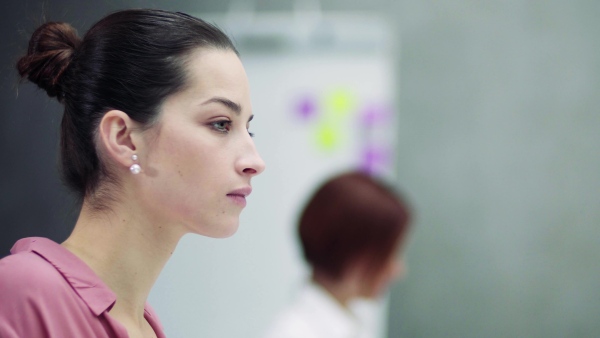 A close-up of young businesswoman sitting in office, working on computer.