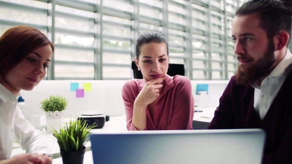 A group of young businesspeople working together in office, talking.