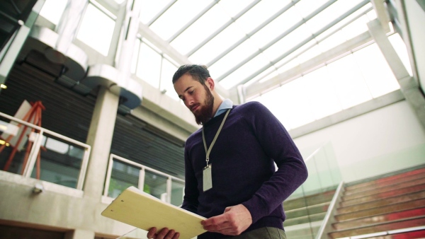 A young hipster businessman walking down the stairs in office building. Slow motion.