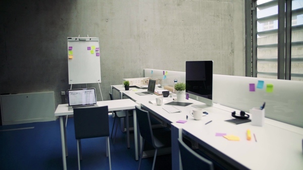 Laptops, blueprints on screens and model of a house in interior of office of architects. Slow motion.