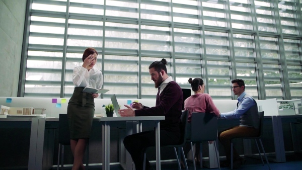 A group of young businesspeople working together in office, talking. Slow motion.