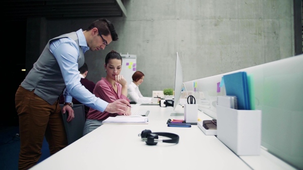 A group of young businesspeople working together in office, talking. Slow motion.