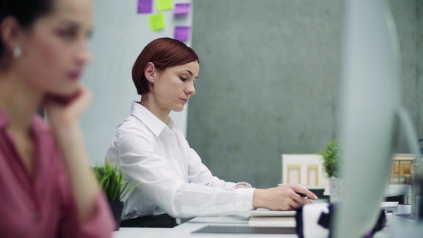 A female young businesswoman or architect in office, working. Slow motion.