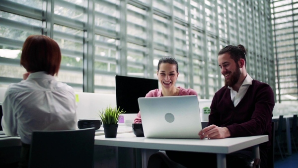 A group of young businesspeople working together in office, talking. Slow motion.