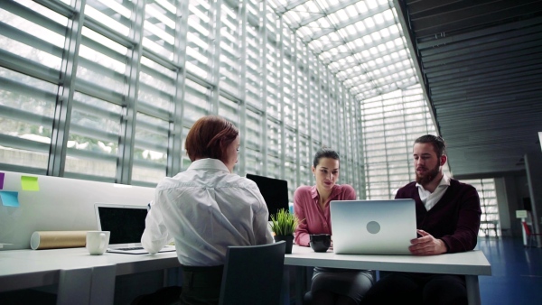 A group of young businesspeople working together in office, talking. Slow motion.