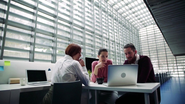 A group of young businesspeople working together in office, talking. Slow motion.