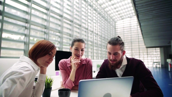 A group of young businesspeople working together in office, talking. Slow motion.