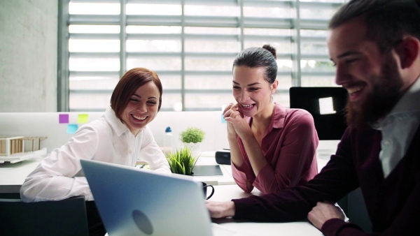 A group of young businesspeople working together in office, talking. Slow motion.