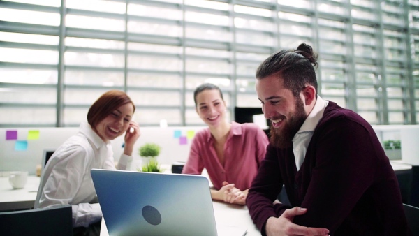 A group of young businesspeople working together in office, talking. Slow motion.