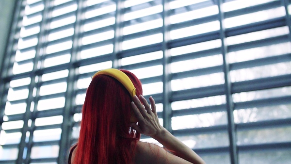 A rear view of woman with headphones in office,listening to music. Slow motion.