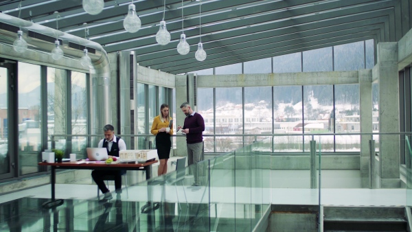 Group of architects with model of a house standing in office, working and talking.