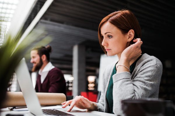 Two young business people working in office, using laptop.