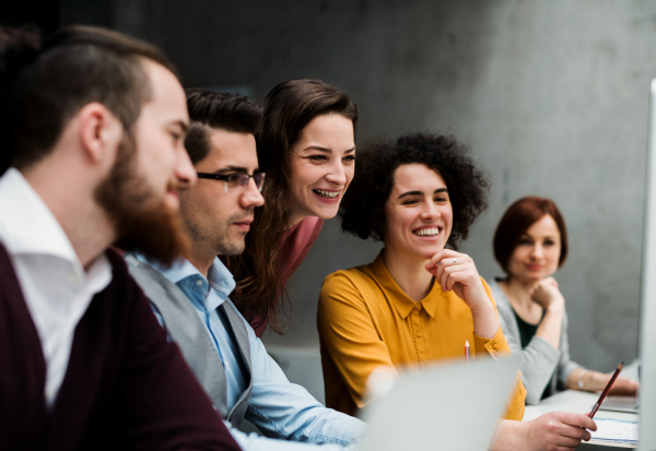 A group of young cheerful businesspeople working together in office, talking.