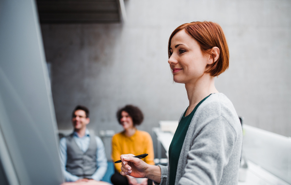 A group of young businesspeople in office, listening to a presentation.