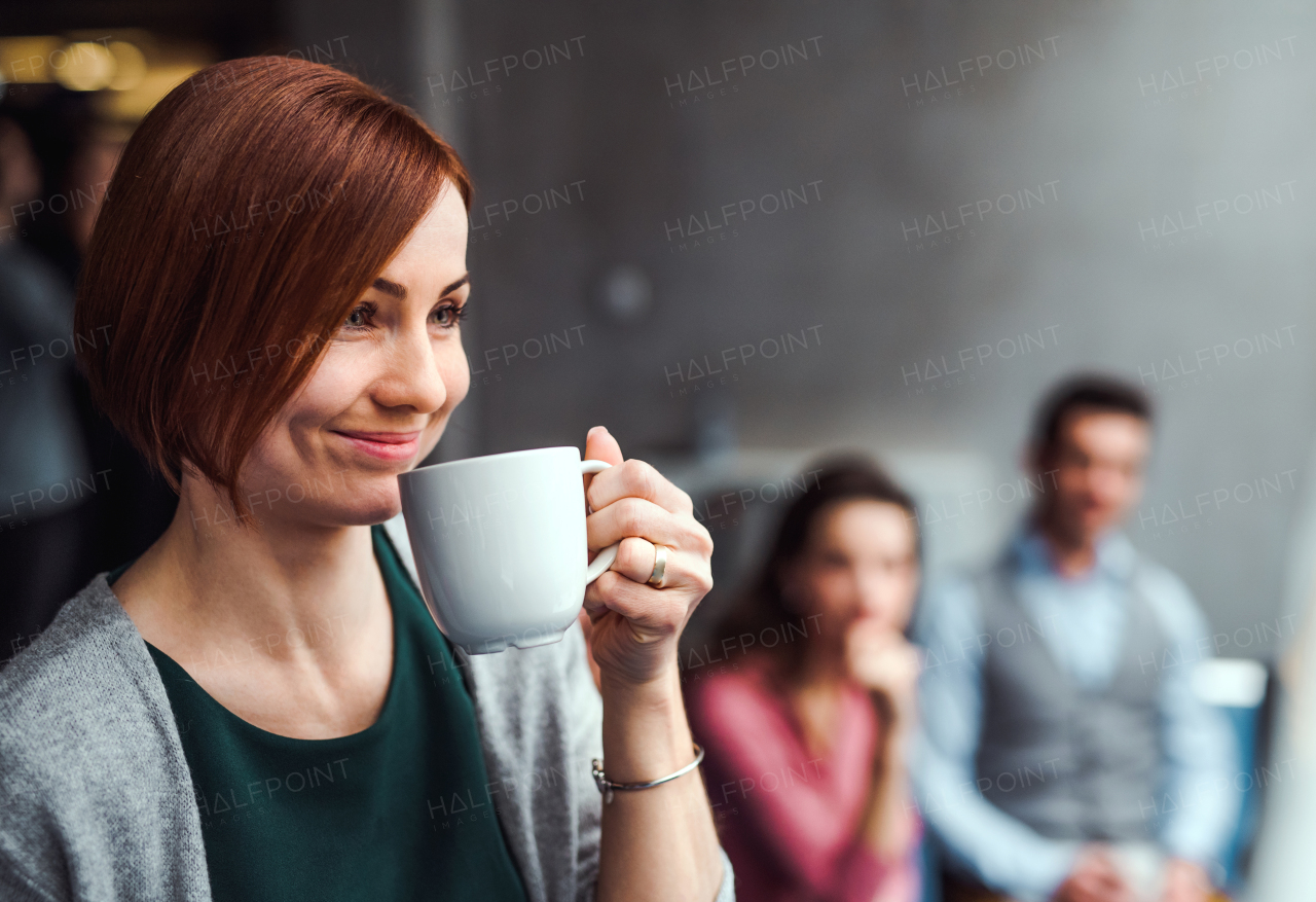 A group of young businesspeople with coffee sitting in office.