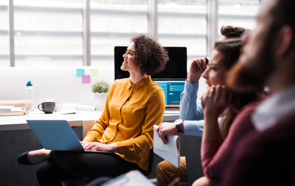 A group of young businesspeople in office, listening to a presentation.