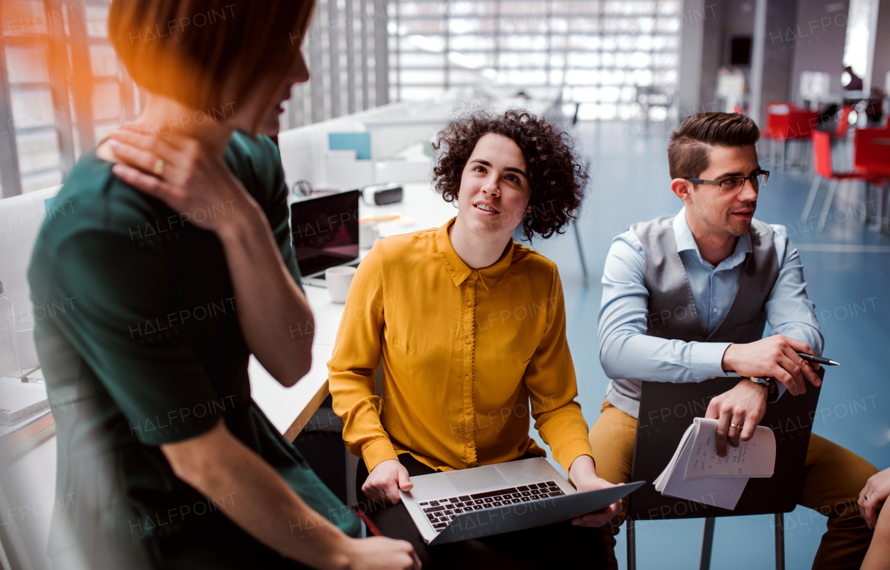 A group of young businesspeople working together in office, talking.