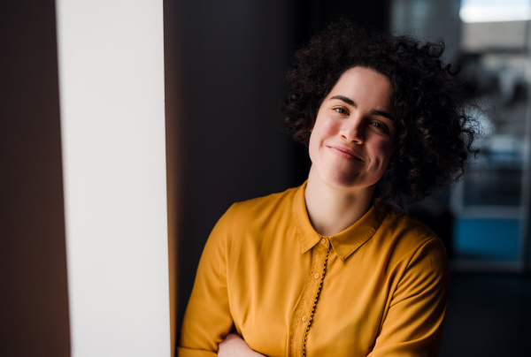 Portrait of a young cheerful businesswoman indoors in an office. Copy space.