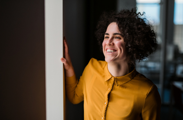 Portrait of a young cheerful businesswoman indoors in an office. Copy space.