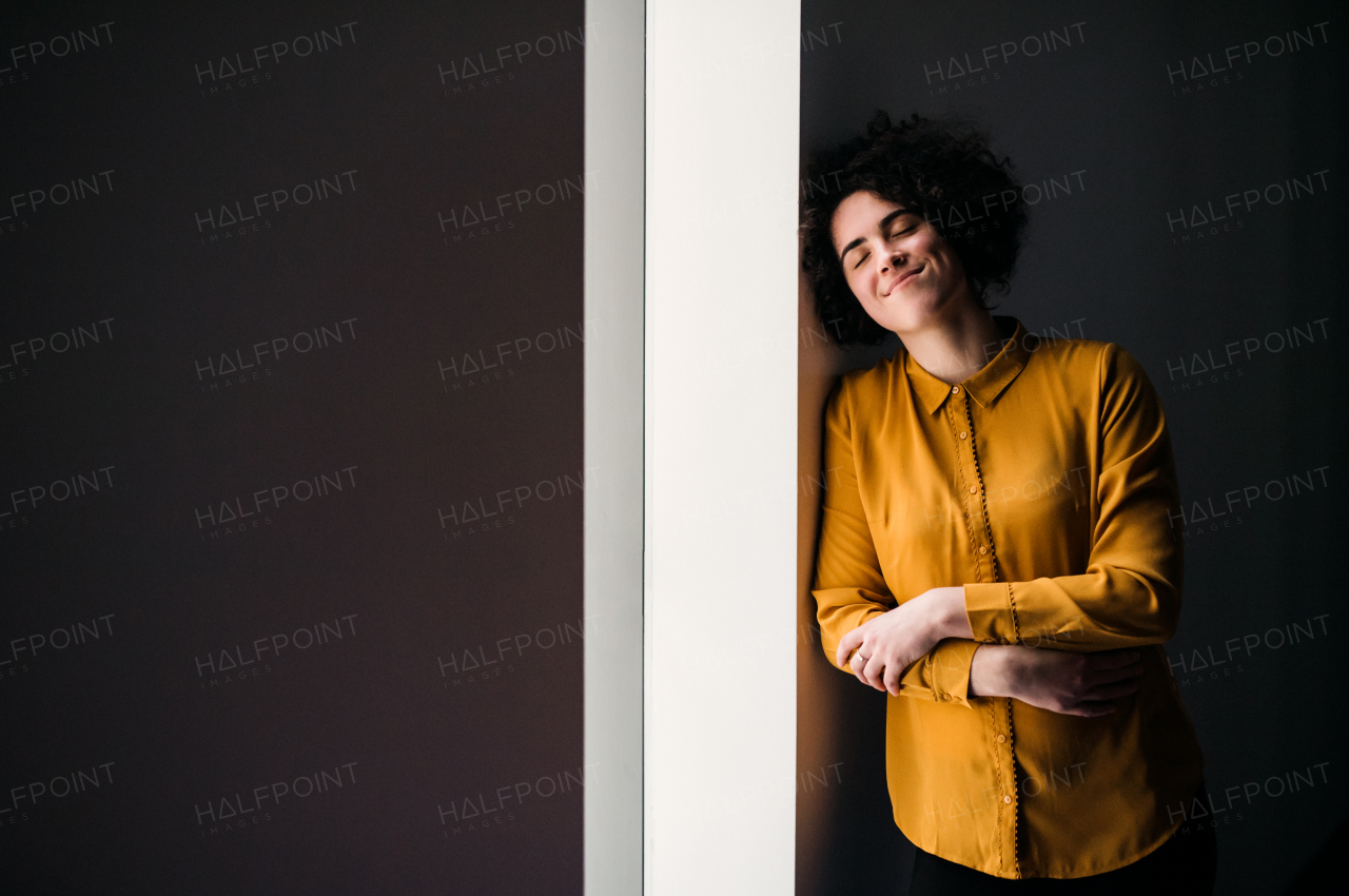 Portrait of a young cheerful businesswoman indoors in an office, resting. Copy space.