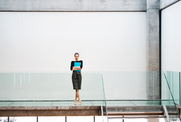 A young businesswoman standing by stairs in office building. Copy space.