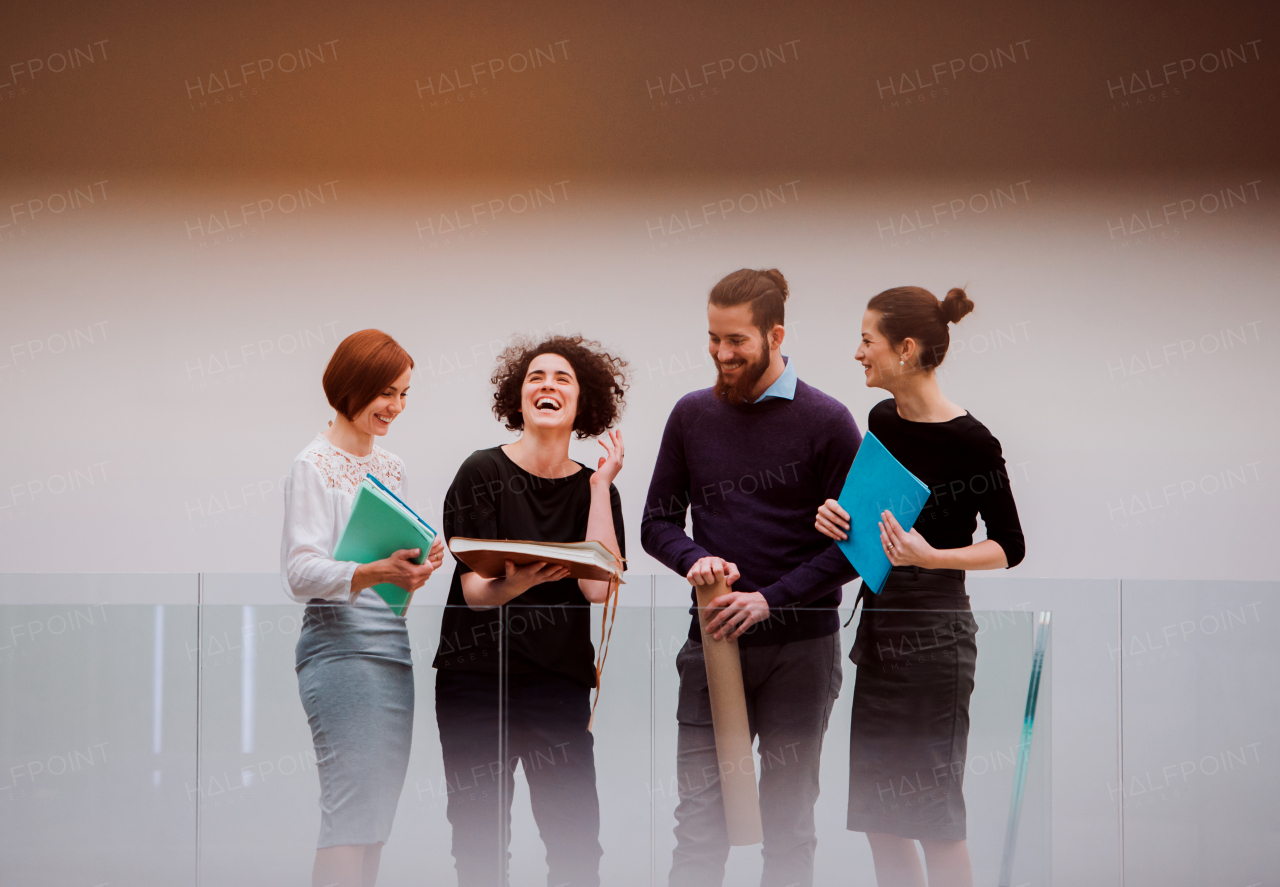 Group of young businesspeople standing in corridor in office building, talking.