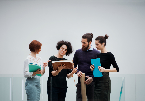 A group of young businesspeople standing in an office, talking.