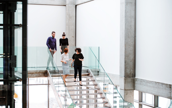 A group of young businesspeople walking down the stairs, talking.