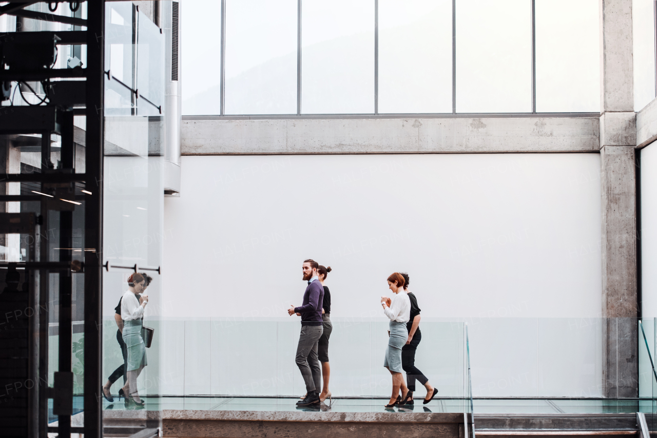 A group of young businesspeople at work, walking in the building.