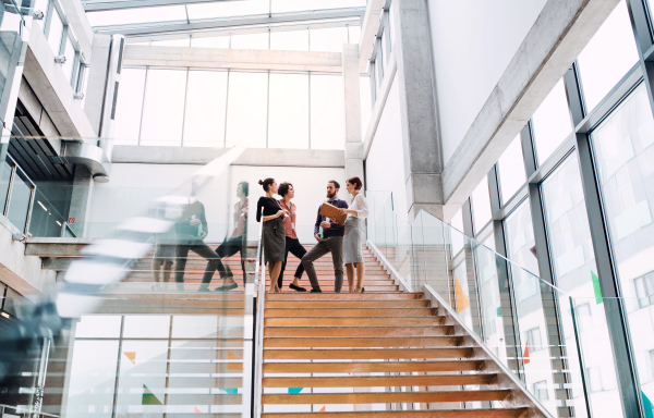 A group of young businesspeople standing on a staircase, talking.