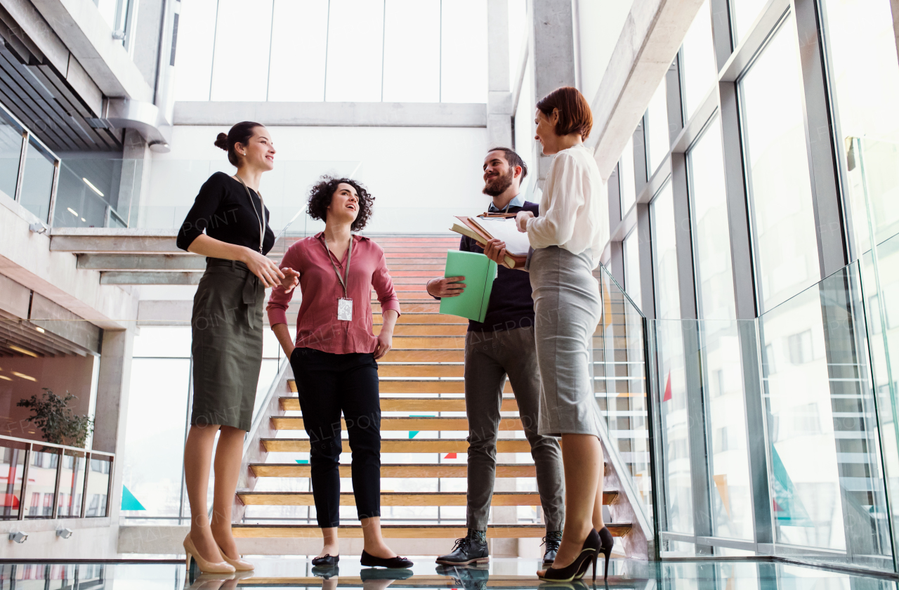 A group of young businesspeople standing near a staircase, talking.