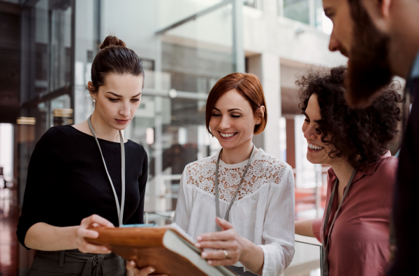 A group of young businesspeople standing together in office, talking.