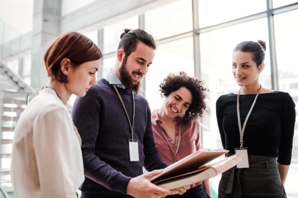 A group of young businesspeople standing near a staircase, talking.